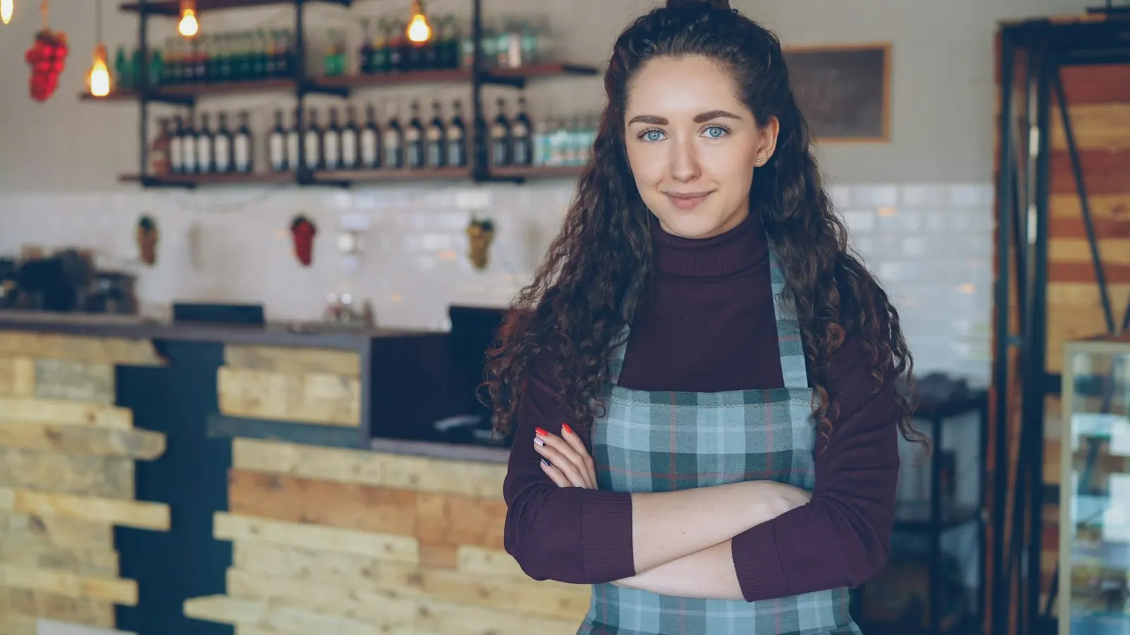 Dueña de una cafetería sonriendo detrás del mostrador de su negocio recién abierto